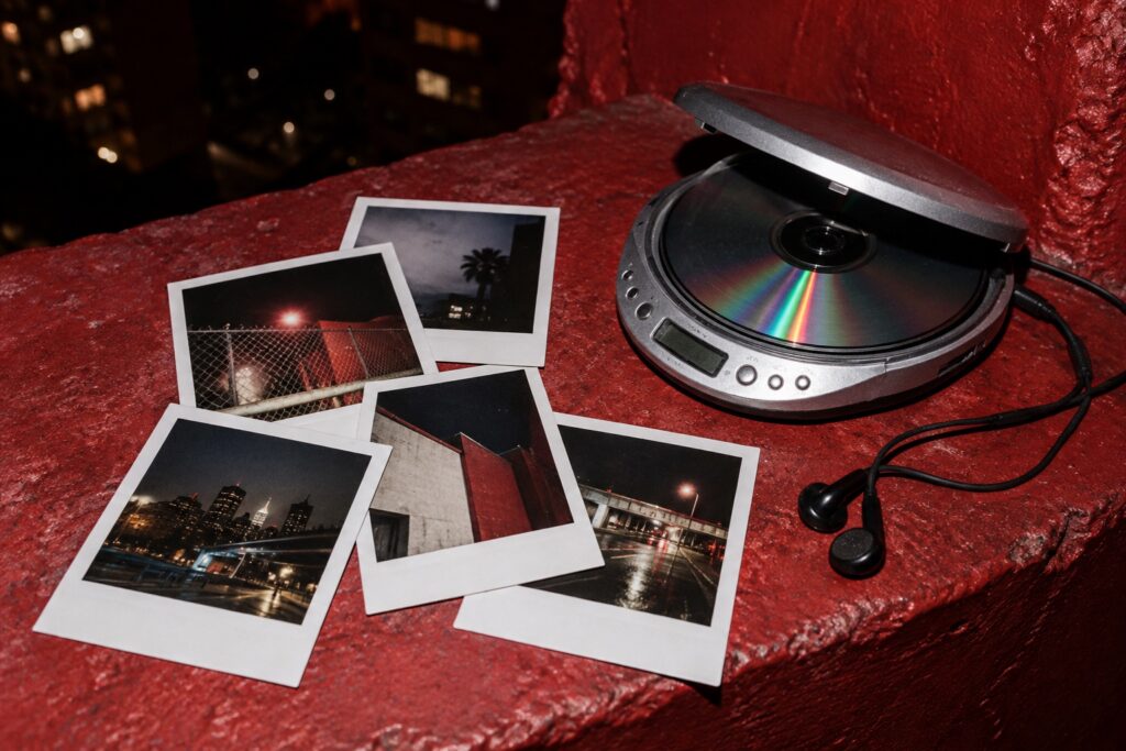 A portable CD player and concert photo prints on a red ledge.